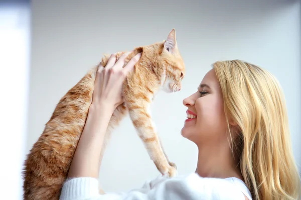 Mulher detém gato vermelho nas mãos — Fotografia de Stock