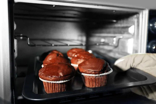Huisvrouw voorbereiding chocolade cupcakes in oven, close-up — Stockfoto