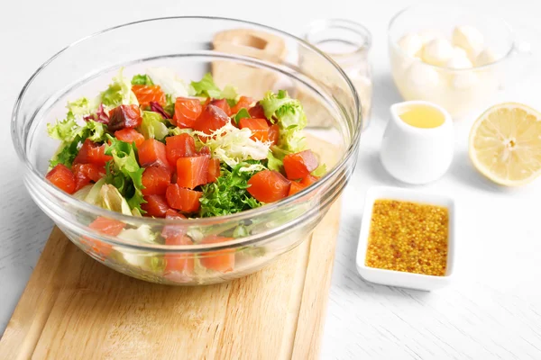 Salade savoureuse dans un plat en verre sur fond de table en bois de couleur — Photo