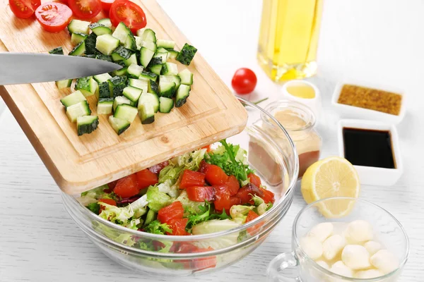 Mani femminili che aggiungono verdure in boccia con insalata, primo piano — Foto Stock