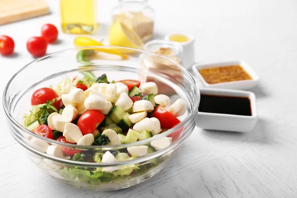 Leckerer Salat in Glasschale auf farbigem Holztischhintergrund — Stockfoto