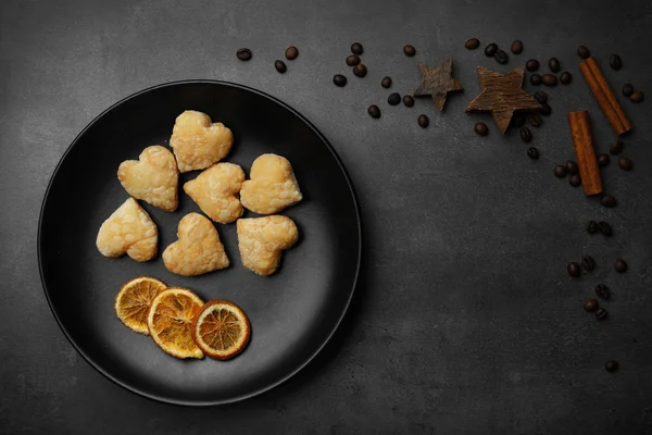 Herzförmige Kekse auf Pfanne mit getrockneten Gewürzen auf dunkelgrauem Hintergrund — Stockfoto