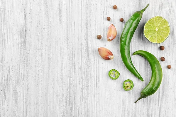 Green chili peppers, garlic, lemon lime on light wooden background — 스톡 사진