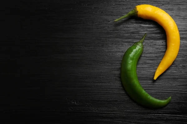 Yellow and green chili peppers on dark wooden background — Stock fotografie