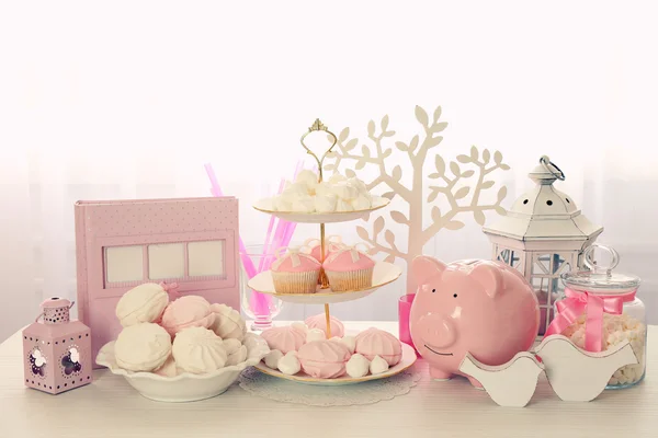 Cupcakes saborosos com arco e sapatos de bebê, carruagem de bebê decorativa no fundo de cor — Fotografia de Stock