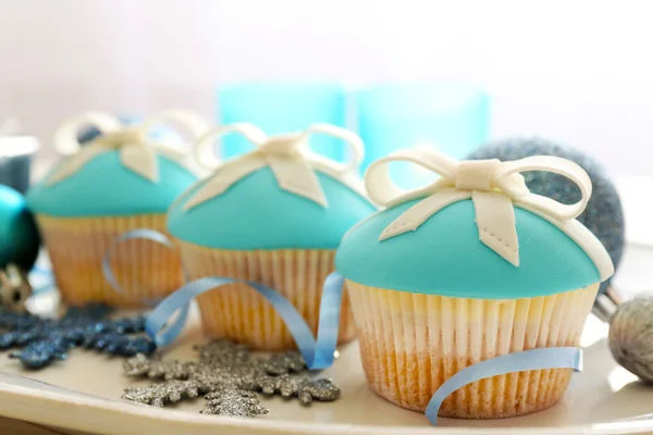 Leckere Cupcakes mit Schleife und Weihnachtsspielzeug auf farbigem Holzhintergrund — Stockfoto