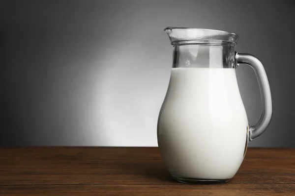 Jar of milk on wooden table on dark background — Stockfoto