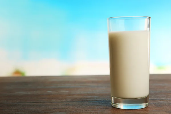 Glas melk op tafel op wazig natuurlijke achtergrond — Stockfoto