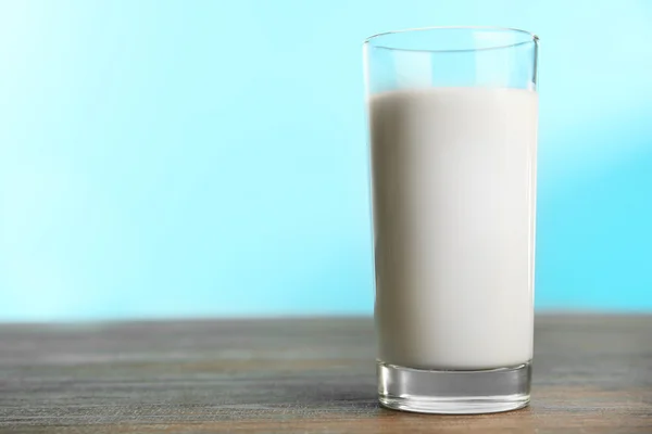 Glass of milk on table on blue background — Stok fotoğraf