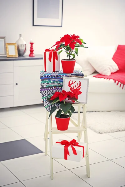 Flor de Navidad poinsettia y decoraciones en escalera decorativa con decoraciones de Navidad, sobre fondo claro — Foto de Stock