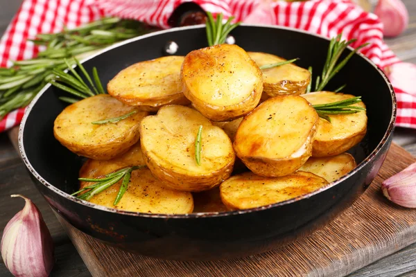 Batata assada deliciosa com alecrim na frigideira na mesa close-up — Fotografia de Stock