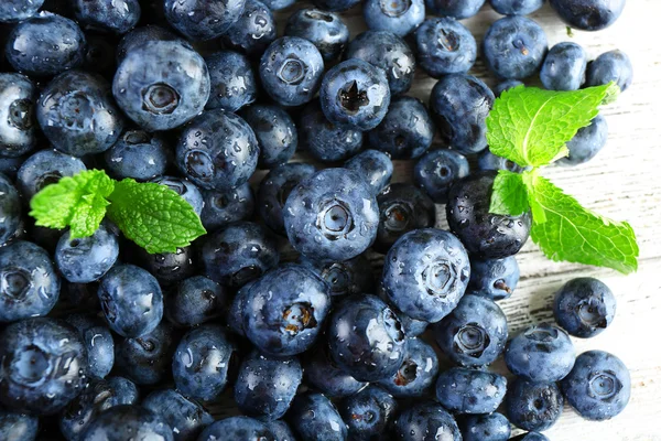 Tasty ripe blueberries with green leaves close up — Stock Photo, Image