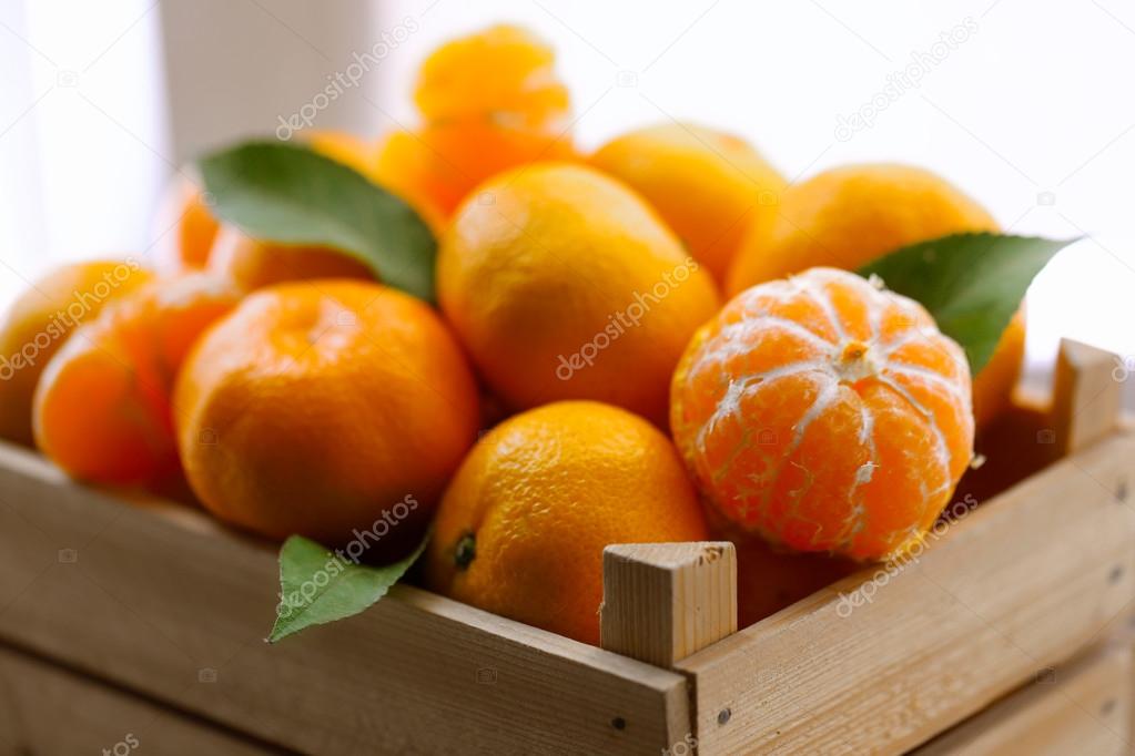 Tangerines in wooden crate, on old wooden table, close up