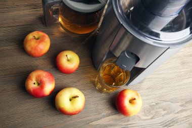 Paslanmaz suyu çıkarıcı ile elma ve bardak suyu ahşap arka plan üzerinde kapat