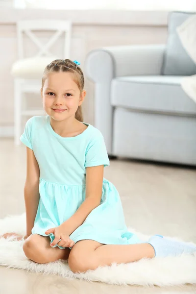 Pequena menina bonito sentado no tapete — Fotografia de Stock