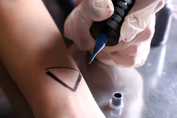 Tattooist drawing triangle — Stock Photo, Image