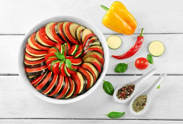 Ratatouille, plat de légumes cuits aux tomates, courgettes, aubergine avant cuisson dans une casserole, sur fond bois — Photo