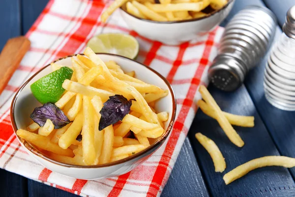 Batatas fritas francesas em tigela com manjericão e molho no fundo de madeira velho — Fotografia de Stock