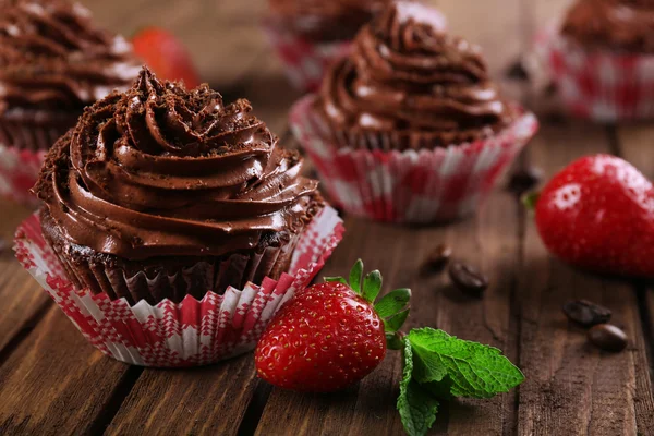 Chocolate cupcakes and strawberries on wooden background — Stock Photo, Image