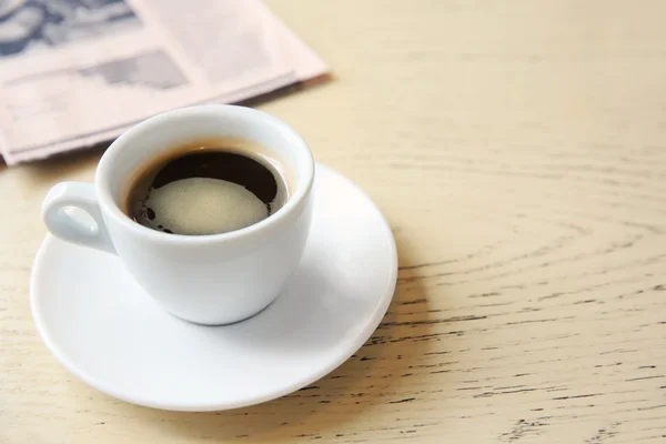 Xícara de café saboroso com jornal na mesa — Fotografia de Stock