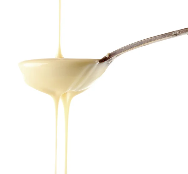 Condensed milk pouring from a spoon, isolated on white — Stock Image Condensed milk pouring from a spoon, isolated on white — Stock Photo, Image