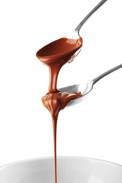 Melted milk chocolate pouring from spoons, isolated on white — Stock Photo, Image