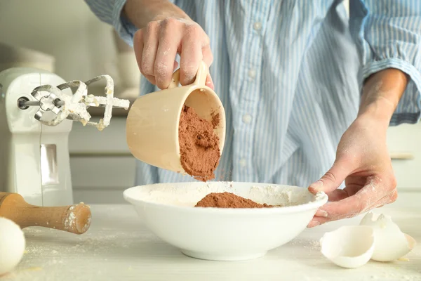 Woman is adding cocoa to the dough — Stock Photo, Image