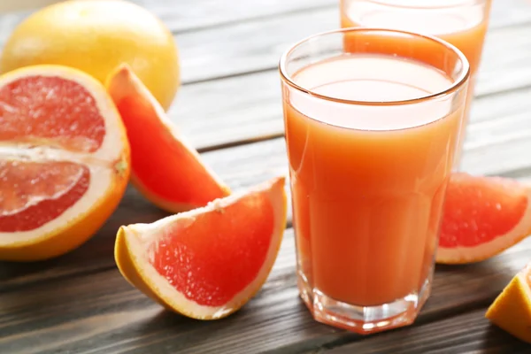 Glass of grapefruit juice and fresh fruits on wooden background