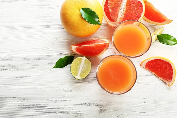 Dois copos de suco cítrico e frutas frescas em fundo de madeira leve — Fotografia de Stock