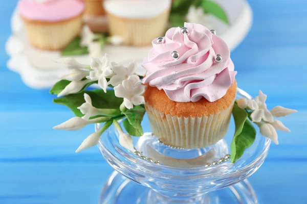 Leckere Cupcakes am Stand, auf farbigem Holzhintergrund — Stockfoto