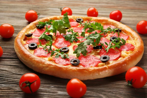 Pizza saborosa com salame decorado com tomates em fundo de madeira, close-up — Fotografia de Stock