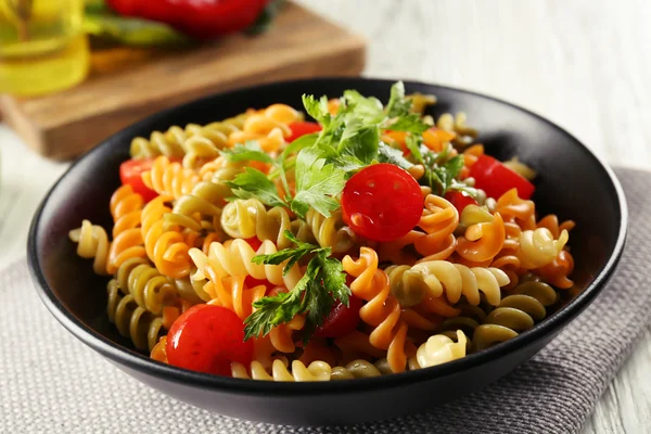 Delicioso plato de macarrones en tazón negro sobre mesa de madera gris servida — Foto de Stock