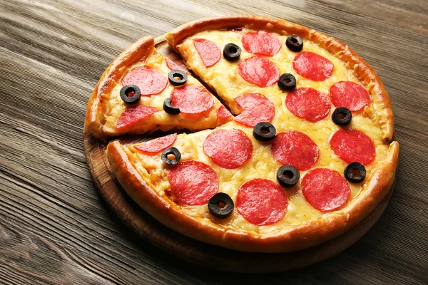 Pizza chaude savoureuse avec salami et olives sur fond de bois — Photo