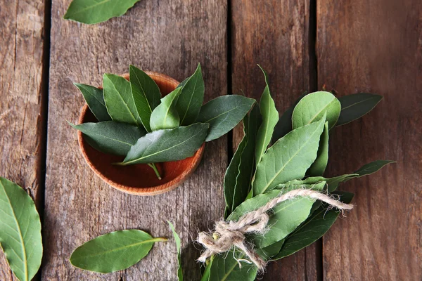 Fresh bay leaves in bowl on vintage wooden table — Stock Photo, Image