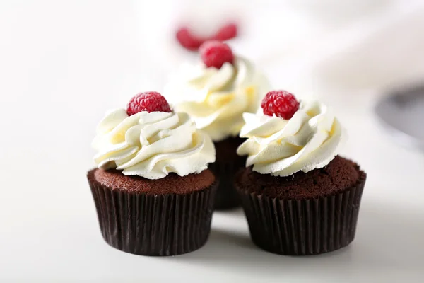 Beautiful chocolate cupcakes with cream and raspberry on table Stock Photo