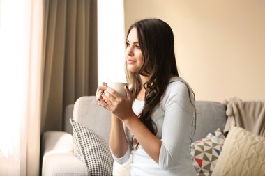 Güzel bir fincan kahve ile odasında kanepede rahatlatıcı kadın