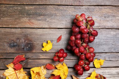 Üzüm ve ahşap arka plan üzerinde renkli yaprakları
