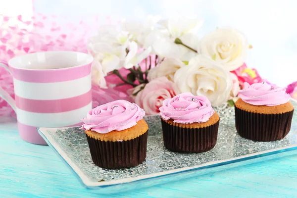 Smakelijke cupcakes op plaat, op een houten achtergrond kleur — Stockfoto