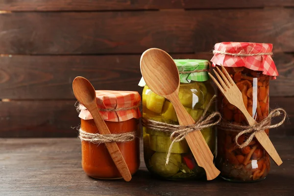 Ahşap arka plan üzerinde turşu sebzeli kavanoz