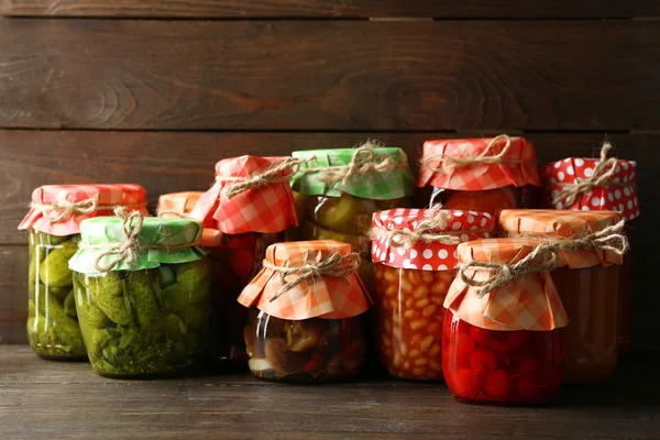 Jars with pickled vegetables and beans on wooden background — Stock Photo, Image