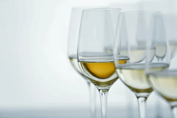 Weingläser mit Weißwein auf Holztisch vor hellem Hintergrund — Stockfoto