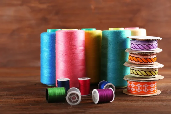 Spools of color ribbon and thread on wooden background — Stock Photo, Image