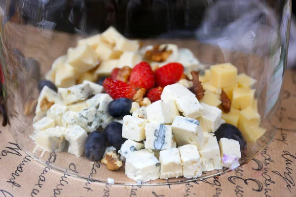 Cheese and berries under glass bowl on table