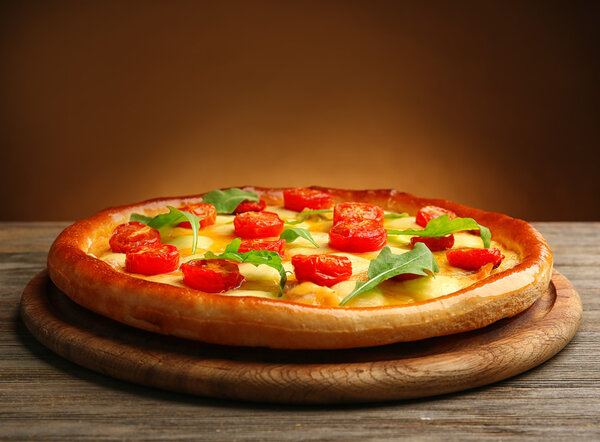 Пицца Маргарита с рукколой на коричневом фоне
