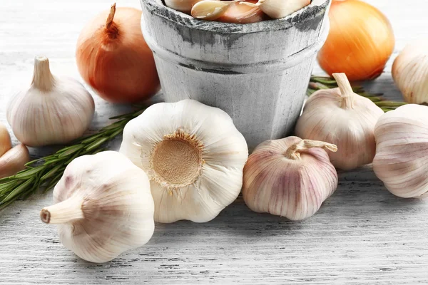 Composición de ajo, cebolla y romero sobre mesa de madera, de cerca —  Fotos de Stock