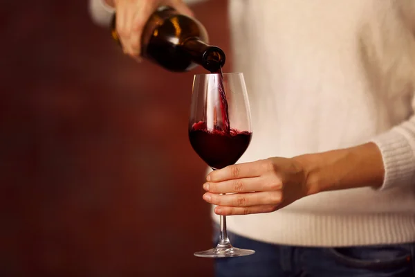 Jovem mulher derramando vinho tinto em vidro no fundo borrado — Fotografia de Stock