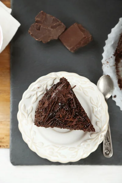 Нарезанный шоколадный торт на деревянном столе, на светлом фоне — стоковое фото