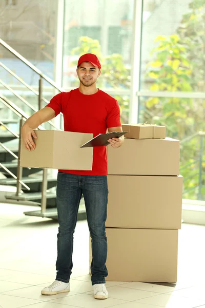 Postbode in rood uniform pakketje — Stockfoto