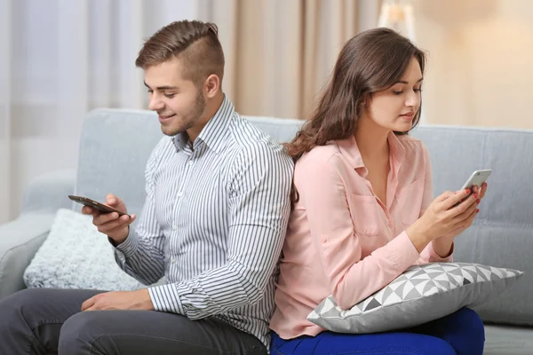 Casal com telefones celulares em casa — Fotografia de Stock