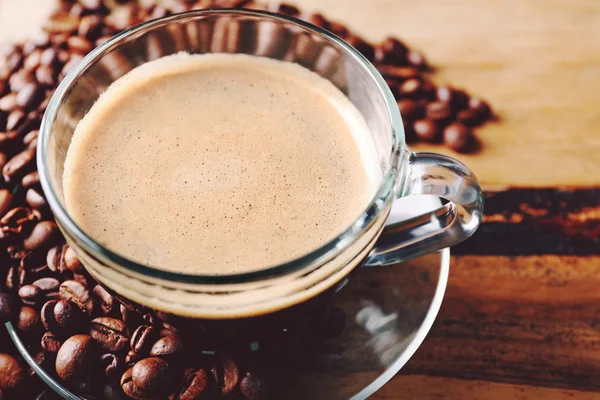 Secangkir kopi dan biji-bijian kopi dengan latar belakang meja kayu — Stok Foto